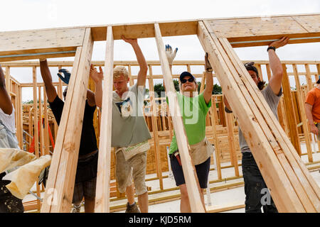 I volontari di sollevamento parete incorniciato al sito in costruzione Foto Stock