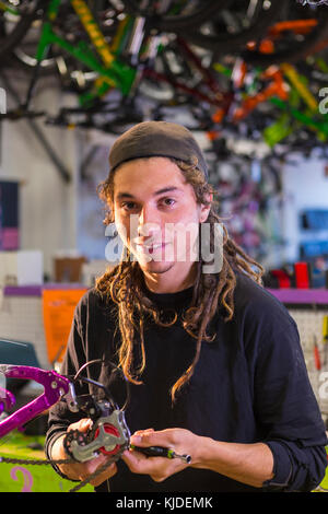 Ritratto di uomo sorridente riparazione bicicletta in negozio Foto Stock