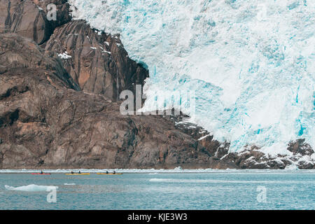 Persone lontane kayak vicino a Glacier Foto Stock