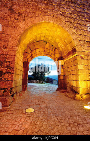 Porta cittadina medievale illuminata notturna con vicolo lastricato di ciottoli Foto Stock