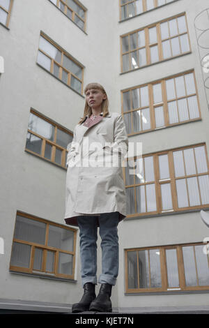 Caucasian donna che indossa un cappotto vicino all'edificio Foto Stock