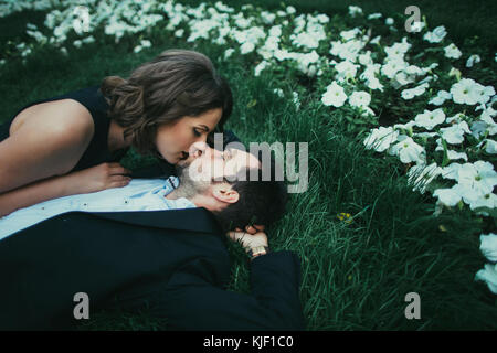 Coppia caucasica posa in erba kissing Foto Stock