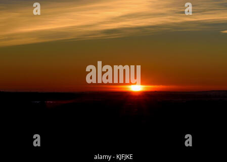 Un bellissimo tramonto rosso con il sole sullo sfondo di cirrus nuvole nel cielo in Inverno gelido giorno Foto Stock