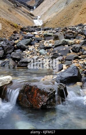 Cascata di Innra Hvannagil canyon di riolite presso la catena montuosa di Dyrfjoll con acqua limpida che scorre su roccia rossa, Eastfjords, Islanda Foto Stock
