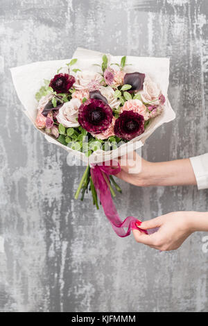 Lusso bellissimo bouquet di fiori misti nella donna la mano. Il lavoro del fioraio presso un negozio di fiori Foto Stock