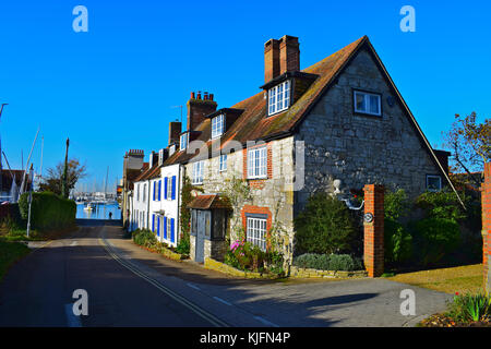 I cieli blu dietro questa bella fila di vecchi marinai'/fishermens' pietra costruito cottages che conducono in basso verso il mare a Shore Road, Warsash, Hampshire Foto Stock