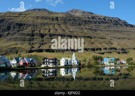 Seydisfjordur case cittadine riflesse in lago fermo con montagne sullo sfondo, Eastfjords, Austurland, Islanda orientale, Scandinavia Foto Stock