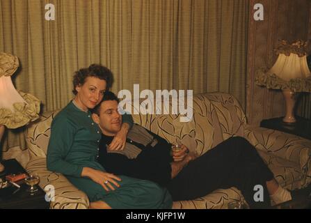 Coppia seduta su un divano, l'uomo appoggiato contro la donna, il braccio della donna intorno al collo dell'uomo, bevendo entrambi da piccoli occhiali, 1952. Foto Stock