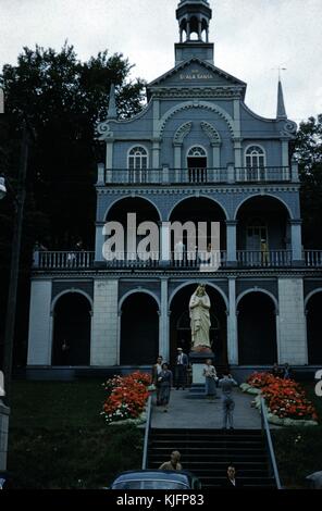 Fotografia a colori della storia di tre strette, edificio, con le parole alla Scala Santa nella parte superiore e una grande statua della Vergine Maria nella parte anteriore, gli uomini e le donne per anni cinquanta costumi, a piedi nella parte anteriore e in posa per le foto, 1952. Foto Stock