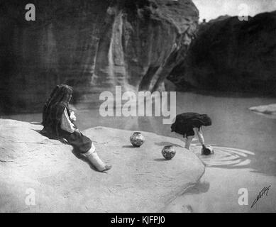 Fotografia di due donne native americane che raccolgono l'acqua in vasetti di argilla in un pozzo, intitolato "The Old Well of Acoma, considerato da molti il villaggio indiano più pittoresco del sud-ovest", di Edward S Curtis, New Mexico, 1904. Dalla New York Public Library. Foto Stock