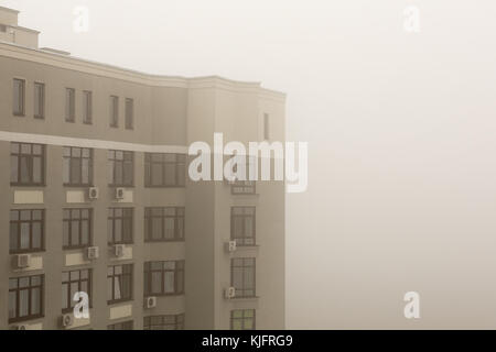 La parte superiore del grattacielo moderno appartamento facciata di edificio durante il pesante velatura meteo. Foto Stock