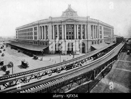 Una fotografia esterna presa da un'elevazione della Stazione Sud, è stata costruita nel 1899 per sostituire diversi terminali ferroviari, serve come un hub di trasporto per autobus, metropolitana, E in treno, si possono vedere dei binari sopraelevati che corrono accanto all'edificio con una piattaforma situata tra di loro, si possono vedere le persone all'esterno dell'edificio insieme a carrozze trainate da cavalli e un tram, Boston, Massachusetts, 1905. Foto Stock