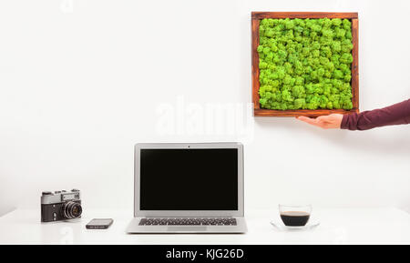 Bussiness minimalista il luogo di lavoro con computer portatile, telefono cellulare, caffè isolato su sfondo bianco. femmina tenendo la mano di pittura di MOSS. moderna contemporar Foto Stock