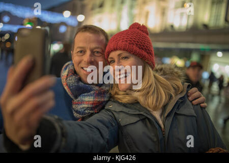 Prendendo un selfie insieme nel centro della città, il tutto avvolto in loro vestiti caldi a causa del freddo christmassy meteo! Foto Stock