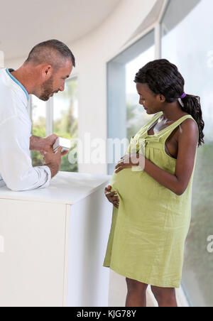 Phamacist in una farmacia che serve una donna in stato di gravidanza che spiega circa il processo di produ Foto Stock