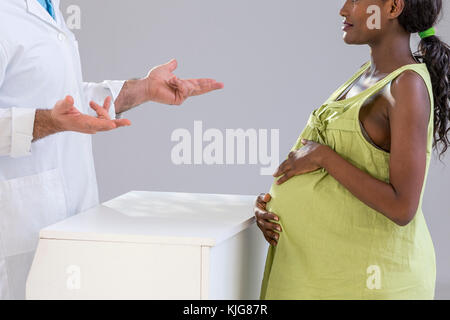 Phamacist in una farmacia spiegando , parlando, una donna in stato di gravidanza. Foto Stock