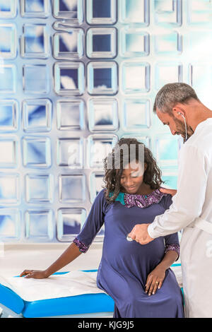 Bello caucasian medico in camice bianco di consulenza è bella african donna incinta nel suo ufficio Foto Stock