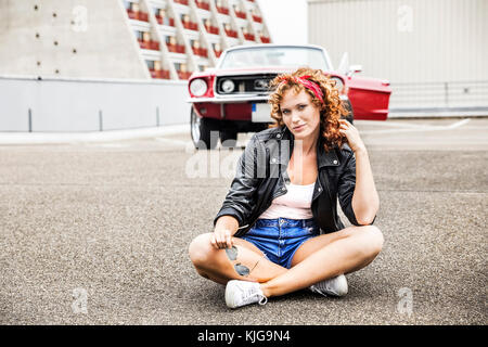 Ritratto di fiducioso redheaded donna seduta sul livello di parcheggio Foto Stock