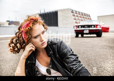 Ritratto di fiducioso redheaded donna seduta sul livello di parcheggio Foto Stock