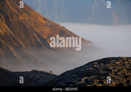 Due persone visto da dietro a piedi lungo il bordo del cratere di un vulcano nella famosa formazione geologica gunung bromo, java, Indonesia. Foto Stock