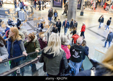 Persone su una scala mobile in un centro commerciale occupato Foto Stock