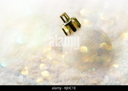 White Christmas tree ball giacenti in banca di neve golden color pastello garland scintillanti luci bokeh festosa atmosfera magica greeting card banner poster tem Foto Stock