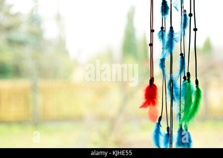 Bella dream catcher da una finestra con blu, verde e rosso e piume Foto Stock