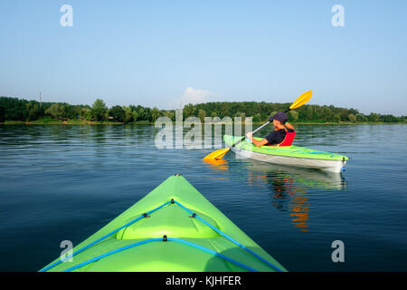 Ragazzo in vita giacca verde sul kayak Foto Stock