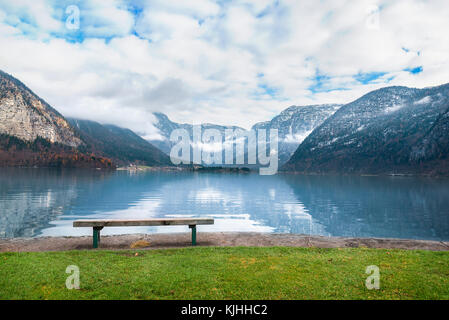 Locazioni vacanze Tema immagine con le montagne del Dachstein si riflette nel lago hallstatter acqua e una panca in legno posto sulla sua riva, in hallstat Foto Stock