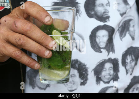 Uomo che indossa un Bob Marley t-shirt & bere un mojito. La Francia. Foto Stock