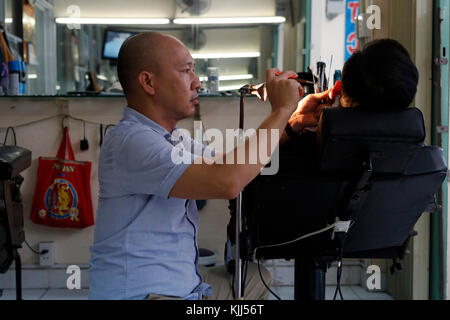 Il vietnamita barbiere. Pulizia dell'orecchio. Ho Chi Minh City. Il Vietnam. Foto Stock