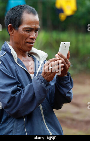 Jarai (Gia Rai) gruppo etnico. Uomo che utilizza uno smartphone. Kon Tum. Il Vietnam. Foto Stock