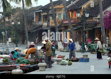 Le donne nel cappello conico con merci per la vendita sul mercato dei prodotti freschi. Hoi An. Il Vietnam. Foto Stock