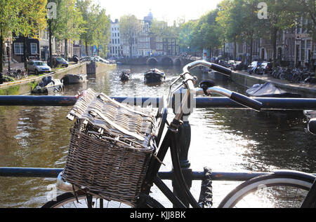 Bicicletta su un ponte sul canale Singel, nel sole autunnale, ad Amsterdam, nei Paesi Bassi Foto Stock