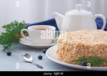 Round multi-layered Napoleone torta con crema pasticcera, su un azzurro sfondo tabella. il fuoco selettivo. cucina russa. Foto Stock