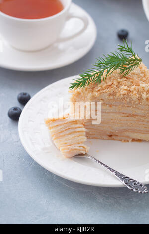 Round multi-layered Napoleone torta con crema pasticcera, su un azzurro sfondo tabella. il fuoco selettivo. cucina russa. Foto Stock