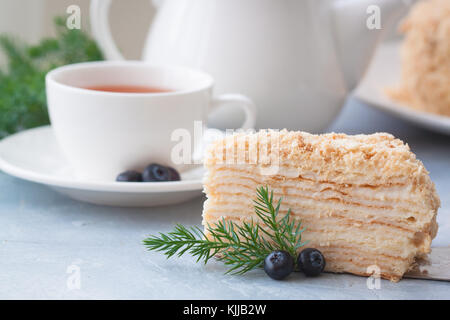 Round multi-layered Napoleone torta con crema pasticcera, su un azzurro sfondo tabella. il fuoco selettivo. cucina russa. Foto Stock