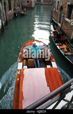 Una barca a motore taxi passando in uno stretto canale di Venezia in Italia Foto Stock