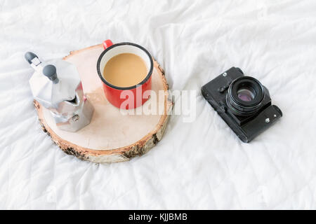 Tazza da caffè con macchina per il caffè sul vassoio con fotocamera vintage sul letto Foto Stock