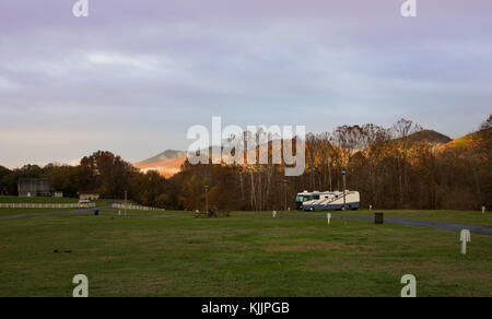 Camper parcheggiato in un campeggio di fronte montagne, al tramonto Foto Stock