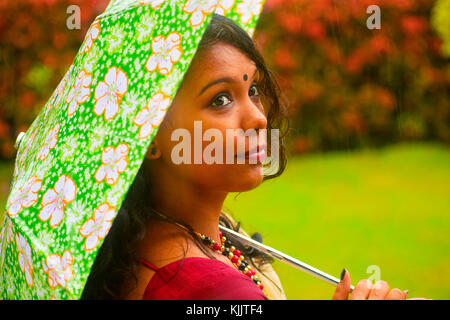 Ragazza indiana in sari che cammina sotto la pioggia con ombrello, Pune, Maharashtra. Foto Stock