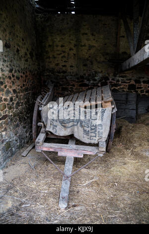 Vecchio carrello nel fienile,carrello, vecchia auto, ruota di carro, vecchia borsa, auto, legno carrello, ruota di carro isolato, stivali da cowboy, occidentale, country-western, diligenze, carro Foto Stock