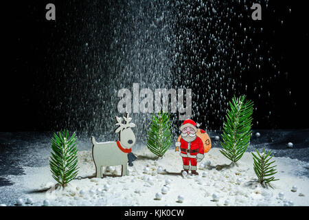 Anno nuovo sfondo. le figure di santa claus, cervi e ragazzo. angelo di neve. nevicava. telaio di notte. billetta per cartoline o congratulazioni. spazio copia Foto Stock