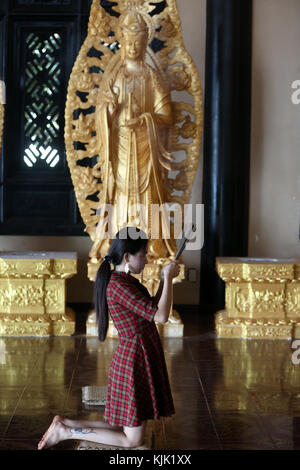 Linh una pagoda buddista. Donna in preghiera tenendo i bastoncini di incenso. Dalat. Il Vietnam. Foto Stock