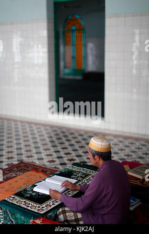 Saigon Moschea centrale. Uomo musulmano la lettura di un Arabo Santo Corano o il Corano. Ho Chi Minh City. Il Vietnam. Foto Stock