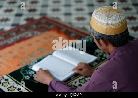 Saigon Moschea centrale. Uomo musulmano la lettura di un Arabo Santo Corano o il Corano. Ho Chi Minh City. Il Vietnam. Foto Stock