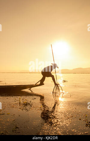 Myanmar Birmania lago Inle tradizionale pescatore di remi Intha gamba pescatori all'alba al tramonto silhouette sagomato Shan Foto Stock