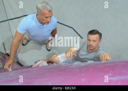 L'uomo imparando a salire sulla parete di arrampicata Foto Stock