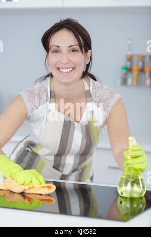 Bella donna di guanti protettivi pulizia armadio cucina Foto Stock