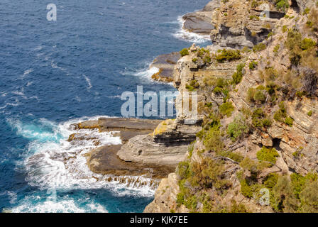 Lentamente ma costantemente onde meteo e erodere le rocce sotto il Devil's kitchen lookout - Eaglehawk Neck, Tasmania, Australia Foto Stock